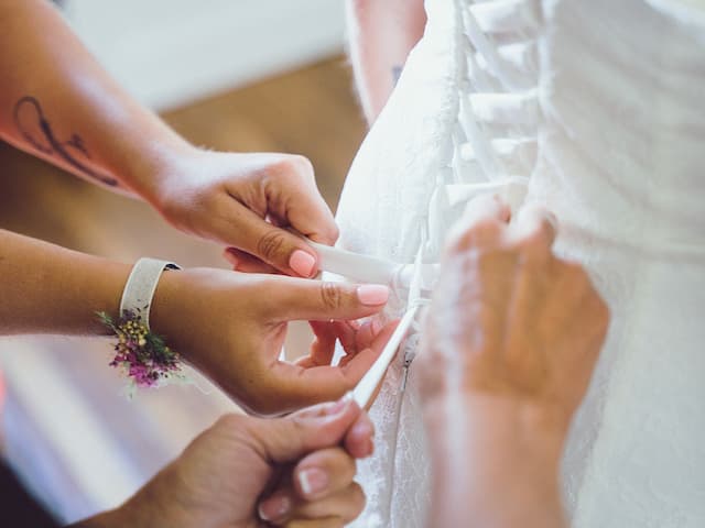 Les petits mains ferme la robe de mariée, par Matthieu Wandolski,  Photographe et Vidéaste de mariage basé dans les Hauts-de-France. Réalise des reportages de mariage de Valenciennes à Arras, Lille et Douai.
